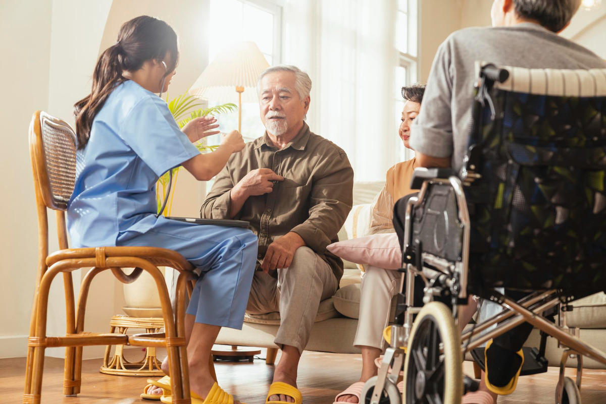 happiness-cheerful-elderly-woman-men-talking-with-female-caregiver-nurse-doctor-having-health-checking-consult-living-areacaretakers-with-senior-couple-sitting-living-room-nursing-home (1)